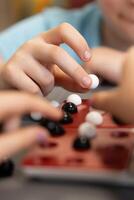 Children gather around the table to play, placing marbles on the game board. Laughter and strategy go hand in hand as they enjoy every move. photo