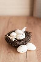A beautiful Easter nest with three white eggs rests on a wooden surface, decorated with delicate feathers and dried flowers. The rustic style and soft natural elements create a cozy and festive Easter photo