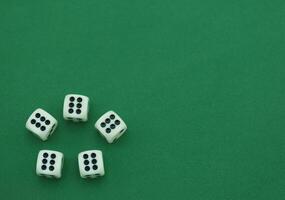 Five white dice arranged on a green surface showing various numb photo