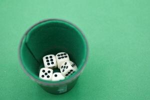 Various dice resting inside a cup on a green felt surface during photo