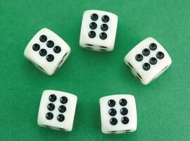 Five white dice showing various numbers on a green background re photo
