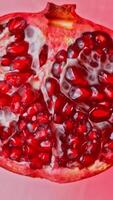 Half of a pomegranate rotating on a light red surface video