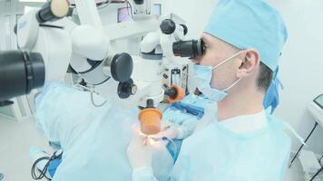 Surgeon looking into the microscope at the eye of female patient at the operating room. Doctor using microscope during eye surgery process, treatment of cataract and diopter correction. 6 video