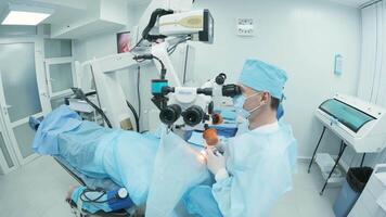 Surgeon looking into the microscope at the eye of female patient at the operating room. Doctor using microscope during eye surgery process, treatment of cataract and diopter correction. 14 video