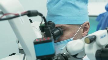 Surgeon looking into the microscope at the eye of female patient at the operating room. Doctor using microscope during eye surgery process, treatment of cataract and diopter correction. 9 video