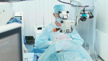 Surgeon looking into the microscope at the eye of female patient at the operating room. Doctor using microscope during eye surgery process, treatment of cataract and diopter correction. 3 video