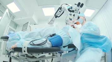 Surgeon looking into the microscope at the eye of female patient at the operating room. Doctor using microscope during eye surgery process, treatment of cataract and diopter correction. 5 video