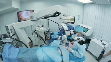 Surgeon looking into the microscope at the eye of female patient at the operating room. Doctor using microscope during eye surgery process, treatment of cataract and diopter correction. 19 video
