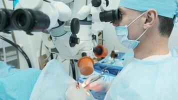 Surgeon looking into the microscope at the eye of female patient at the operating room. Doctor using microscope during eye surgery process, treatment of cataract and diopter correction. 12 video