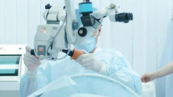Surgeon looking into the microscope at the eye of female patient at the operating room. Doctor using microscope during eye surgery process, treatment of cataract and diopter correction. 8 video