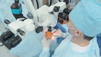 Surgeon looking into the microscope at the eye of female patient at the operating room. Doctor using microscope during eye surgery process, treatment of cataract and diopter correction. 4 video