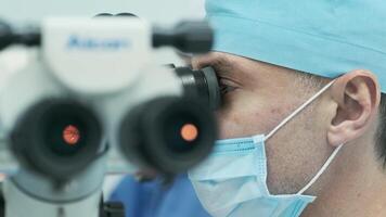 Surgeon looking into the microscope at the eye of female patient at the operating room. Doctor using microscope during eye surgery process, treatment of cataract and diopter correction. video