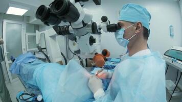 Surgeon looking into the microscope at the eye of female patient at the operating room. Doctor using microscope during eye surgery process, treatment of cataract and diopter correction. 15 video