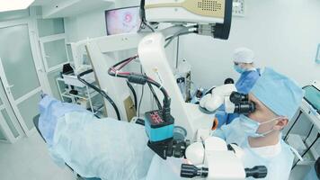 Surgeon looking into the microscope at the eye of female patient at the operating room. Doctor using microscope during eye surgery process, treatment of cataract and diopter correction. 7 video