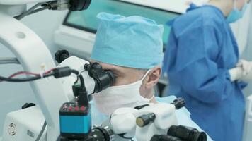 Surgeon looking into the microscope at the eye of female patient at the operating room. Doctor using microscope during eye surgery process, treatment of cataract and diopter correction. 18 video