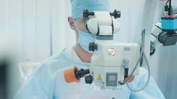 Surgeon looking into the microscope at the eye of female patient at the operating room. Doctor using microscope during eye surgery process, treatment of cataract and diopter correction. 2 video