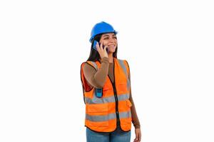 Smiling female engineer talking on smartphone wearing safety helmet and vest photo