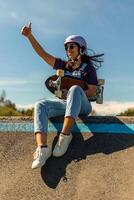 Smiling skater gesturing thumbs up while sitting on pump track ramp photo