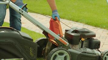 The man starts a self-propelled gasoline lawn mower and cuts high grass using a collection bag. video