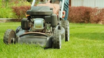 Lawn mower cutting the grass. Gardening activity. Cutting grass with petrol driven lawn mower in sunny garden. Gardener working with mower machine in the garden. Lawn mower cutting green grass 45 video