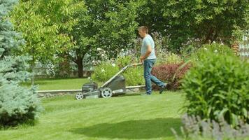 Lawn mower cutting the grass. Gardening activity. Cutting grass with petrol driven lawn mower in sunny garden. Gardener working with mower machine in the garden. Lawn mower cutting green grass 16 video
