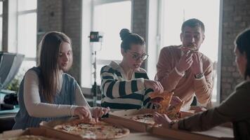 Diverse group of young professionals enjoying pizza together in a modern office space, creating a relaxed and collaborative atmosphere. Teamwork concept, casual meetings, and workplace culture video