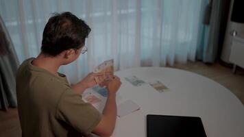 Man counting money. A man meticulously counts a stack of banknotes at a table, conveying a sense of financial planning and responsibility. video