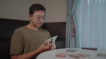Counting cash young man meticulously counting cash at a table, reflecting on his finances and planning for the future. video