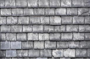 Gray slate roof tiles interlocking tightly, presenting weathered texture and architectural resilience, highlighting traditional roofing craftsmanship with protective surface pattern photo