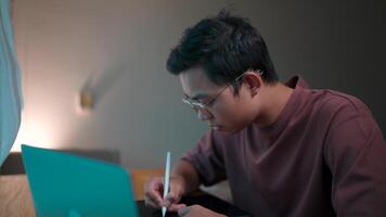 Focused on the task a young man, immersed in his work, meticulously uses a stylus on a digital tablet, his concentration evident in his furrowed brow. video