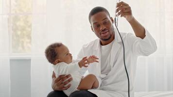 African American toddler is sitting in the lap of a caregiver, engaging in a playful interaction. The indoor environment is well-lit and cozy, creating a nurturing atmosphere for the child. video