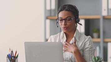A dedicated African American woman teaches students online, utilizing a laptop and headset while creating an interactive and engaging learning environment from her home office. video