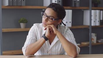 A dedicated teacher is deep in thought while preparing for an online class session. She is surrounded by shelves of educational materials in a modern, well-lit environment. video