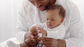 African American toddler expresses discomfort while being checked by a caring adult indoors, highlighting a moment of connection during a health assessment in a bright environment. video