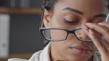 A dedicated African American woman with glasses is engaged in remote teaching. She focuses intently as she interacts with students, creating a supportive learning atmosphere. video