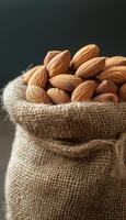 Almond nut in beige sack material organic food un cook and deep grey background photo