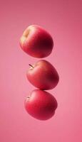 Three red apples fruit floating in air snack real food wallpaper pink background photo