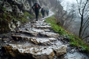 Hikers ascend a muddy stone path on a misty day The path winds along a steep rocky hillside photo