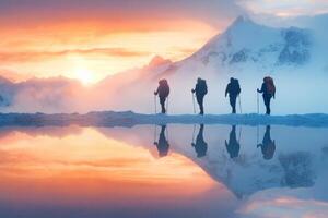 Hikers silhouetted against a stunning sunset reflecting in a mountain lake photo
