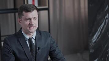 Businessman in suit giving interview, gesturing, and speaking in a modern office setting, close-up shots. video