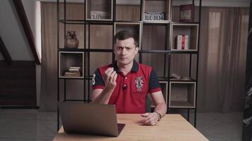 A man in a red polo shirt is giving a presentation in a contemporary home office with a bookshelf in the backdrop video