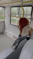 Woman is sitting in bus and posing for photographer. Man with camera walks around salon of public transport and takes photo of model. Red-haired girl in retro clothes and boho fur coat. Backstage. video
