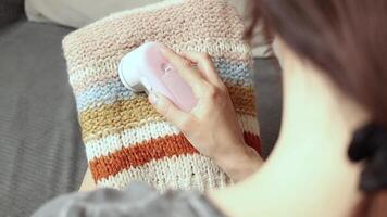 Woman uses a machine for removing pellet and spools from woolly. A modern electronic device for updating old things close up video