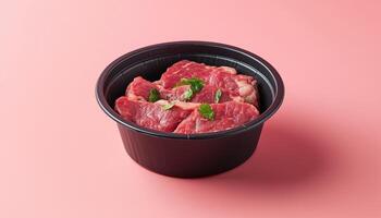 Beef steak slice un cook on black disposable paper bowl on pink background photo