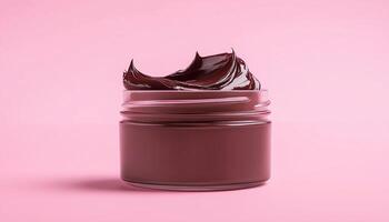 Chocolate cream jam on glass jar with pink solid background photo