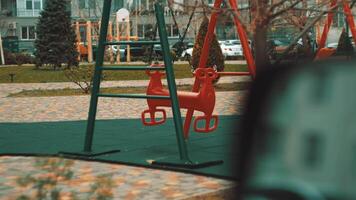 Windy day in a city courtyard. Colorful swings move slowly with the breeze in a quiet, modern housing complex video