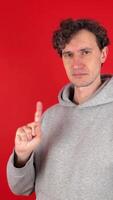 serious man shakes index finger hand in front showing sign ban, rejected gesture. Isolated red background studio shot. Concept - avoid, danger, disapproval, negative emotions, must not, impossible video