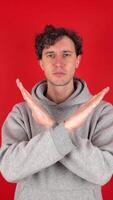 serious man raises hands, crosses arms, showing in front sign stop, ban, rejected gesture. Isolated red background studio shot. Concept - avoid danger disapproval negative emotions must not impossible video