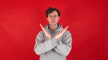 serious man raises hands crosses arms showing in front sign stop ban rejected gesture. Isolated red background studio shot. Concept - avoid danger, disapproval, negative emotions, must not, impossible video