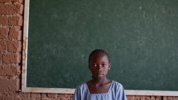 Young student standing in front of a blackboard in a classroom video